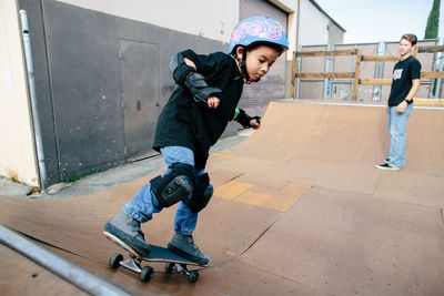 Skater boy riding a half pipe with instructor watching over