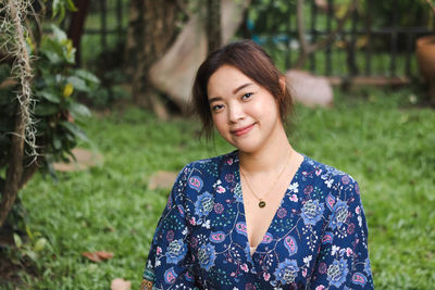 Portrait of young woman standing against plants