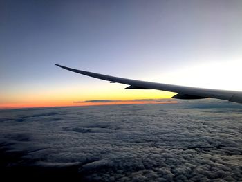 Cropped image of aircraft wing over cloudscape during sunset