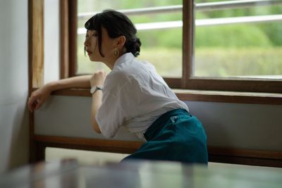 Young woman sitting by window at home