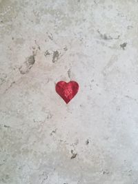 High angle view of red heart shape on white surface