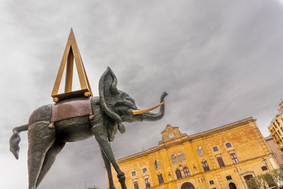 Low angle view of statue against building against sky