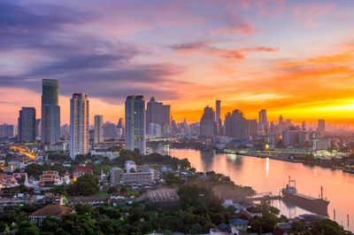 Modern buildings in city against sky during sunset