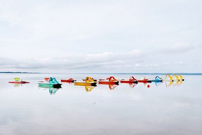 Colorful pedal boats on sea against sky