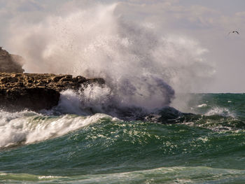 Waves splashing in sea against sky