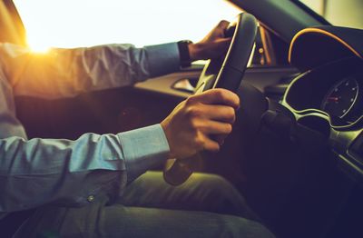 Midsection of man driving car during sunset