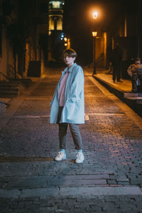 Full length of boy walking on street in city at night