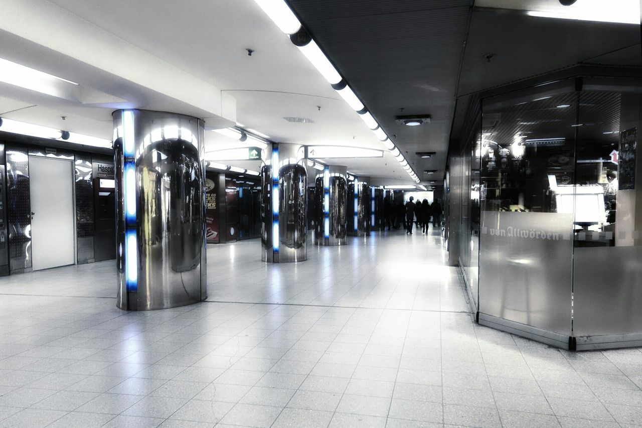 indoors, ceiling, flooring, public transportation, transportation, illuminated, tiled floor, empty, railroad station, modern, incidental people, architecture, built structure, interior, subway station, travel, railroad station platform, in a row, airport, architectural column