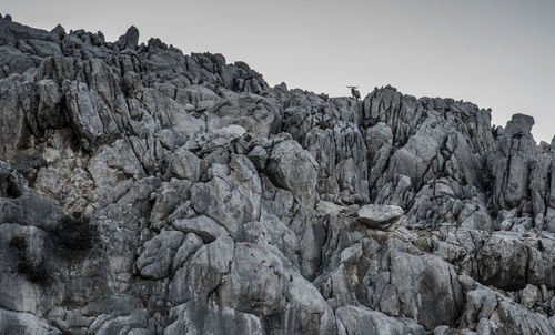 Low angle view of rocky mountains against clear sky