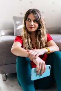 Portrait of beautiful young woman sitting on sofa