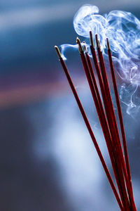 Close-up of incense sticks burning against blurred background