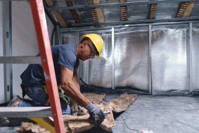 Mature construction worker working on insulation at site