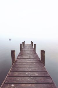 Wooden pier over sea against sky