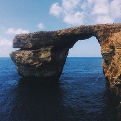 Rock formation by sea against sky
