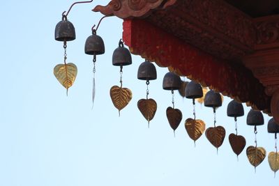 Low angle view of lanterns hanging on roof against sky