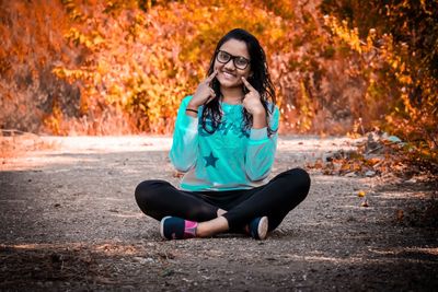 Portrait of young woman sitting in autumn