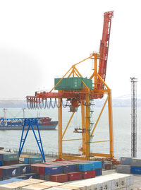 Cranes at harbor against clear sky