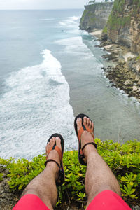 Low section of man relaxing on rock cliff at beach