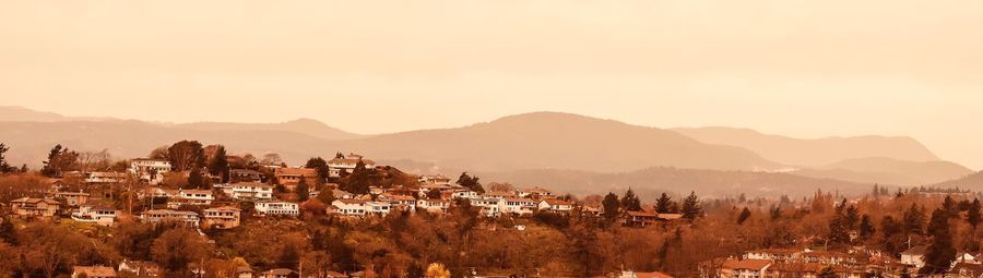 Panoramic shot of townscape by mountains against clear sky