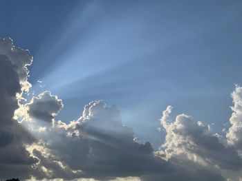 Low angle view of sunlight streaming through clouds