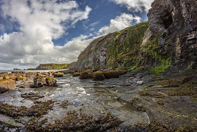 Rock formation on beach against sky