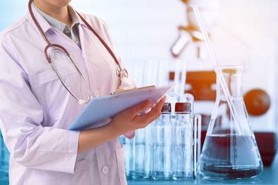 Midsection of female doctor holding clipboard 