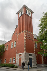 Low angle view of people walking on building against sky