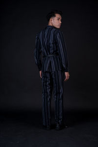 Portrait of young woman standing against black background