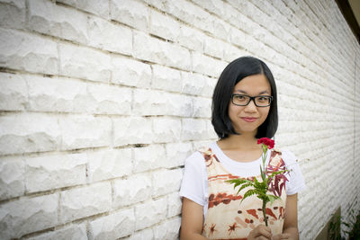 Portrait of beautiful young woman against wall