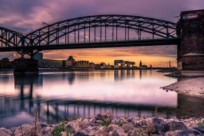 Bridge over river in city during sunset