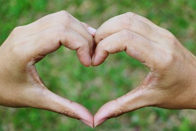 Cropped hands of couple making heart shape