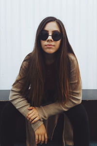 Portrait of young woman wearing sunglasses sitting at home