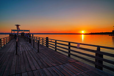 Pier over sea against sky during sunset