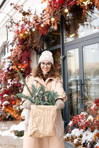 A stylish girl in a hat and coat made a christmas nobilis purchase in the city