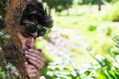 Close-up of man smoking behind tree in forest