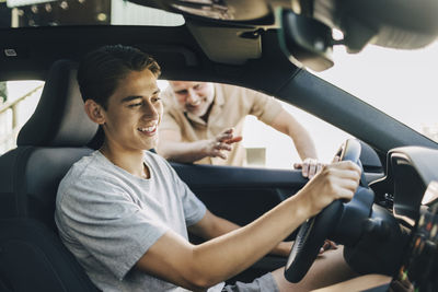 Father assisting son sitting while driving car