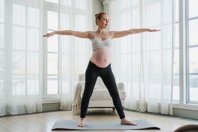 Full length of young woman exercising at home