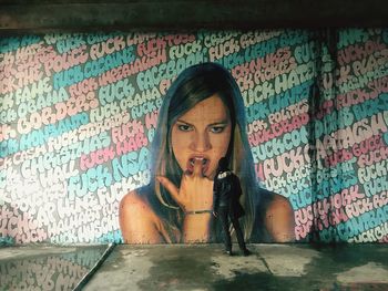 Portrait of young woman against graffiti wall