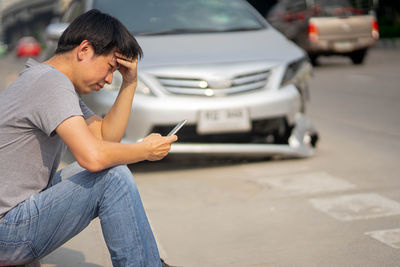 Side view of man using mobile phone in city