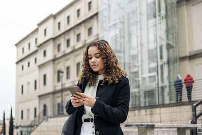 Full length of young woman using phone