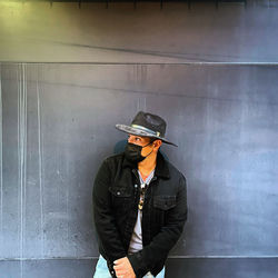 Man holding umbrella standing against wall