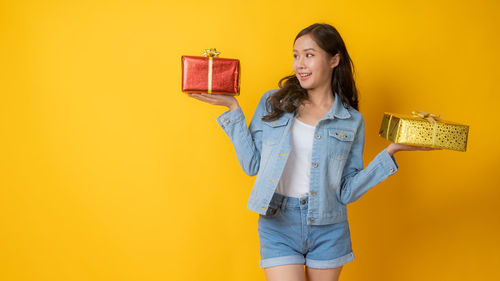 Woman standing against yellow wall