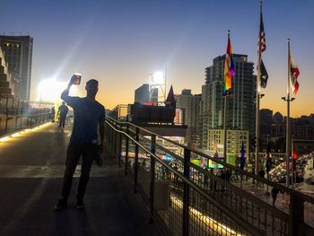 Full length of man standing on illuminated city against clear sky at night