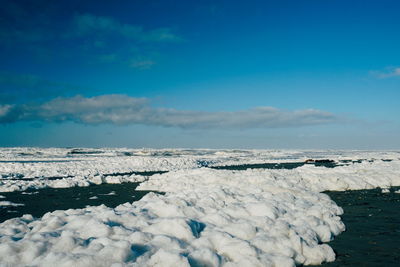 Scenic view of snow covered landscape against blue sky