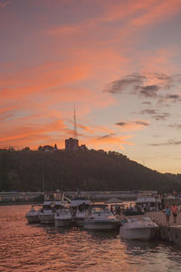 Sailboats moored on river against sky during sunset