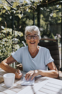 Senior woman sitting in garden and looking at camera