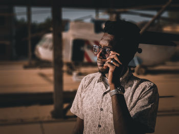 Portrait of young man holding camera while standing outdoors