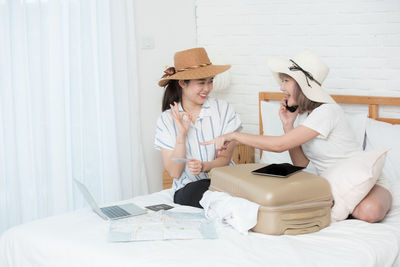 Woman wearing hat sitting against wall