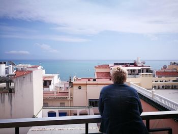 Rear view of man looking at sea from balcony