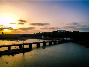 Bridge over river against sky during sunset